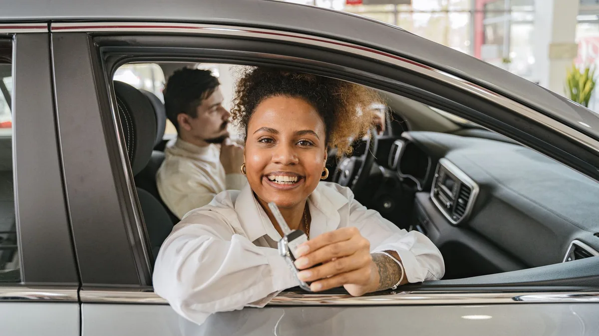 Pessoa recebendo a chave de um carro na concessionária após ser contemplada no consórcio
