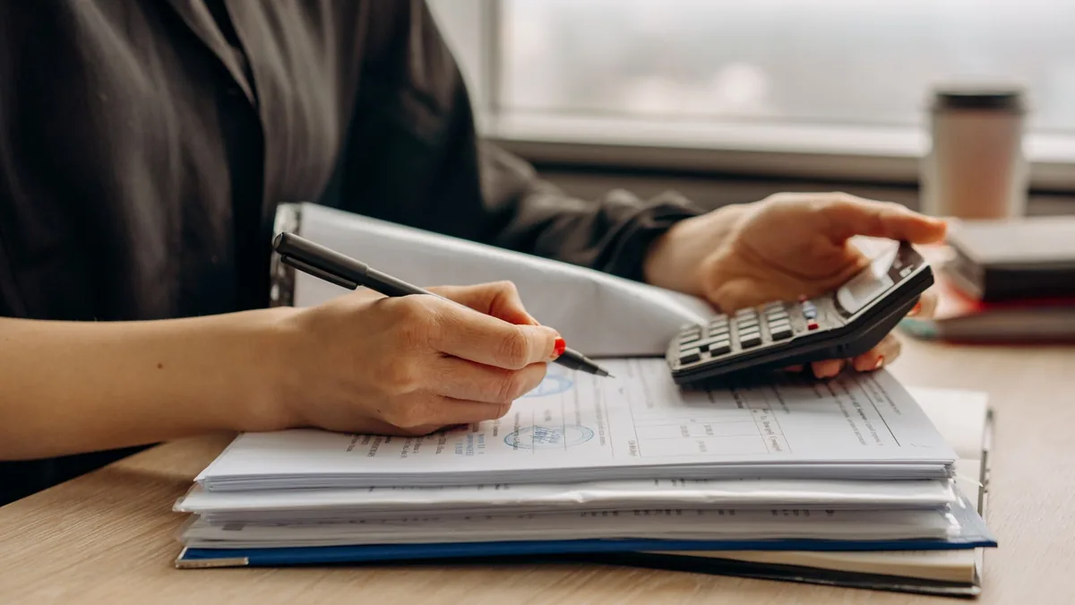 Pessoa comparando propostas de consórcio de carro em uma mesa com calculadora e documentos