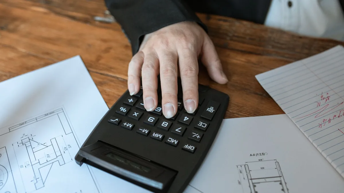 Mesa com planta de imóvel, calculadora e documentos de simulação de consórcio