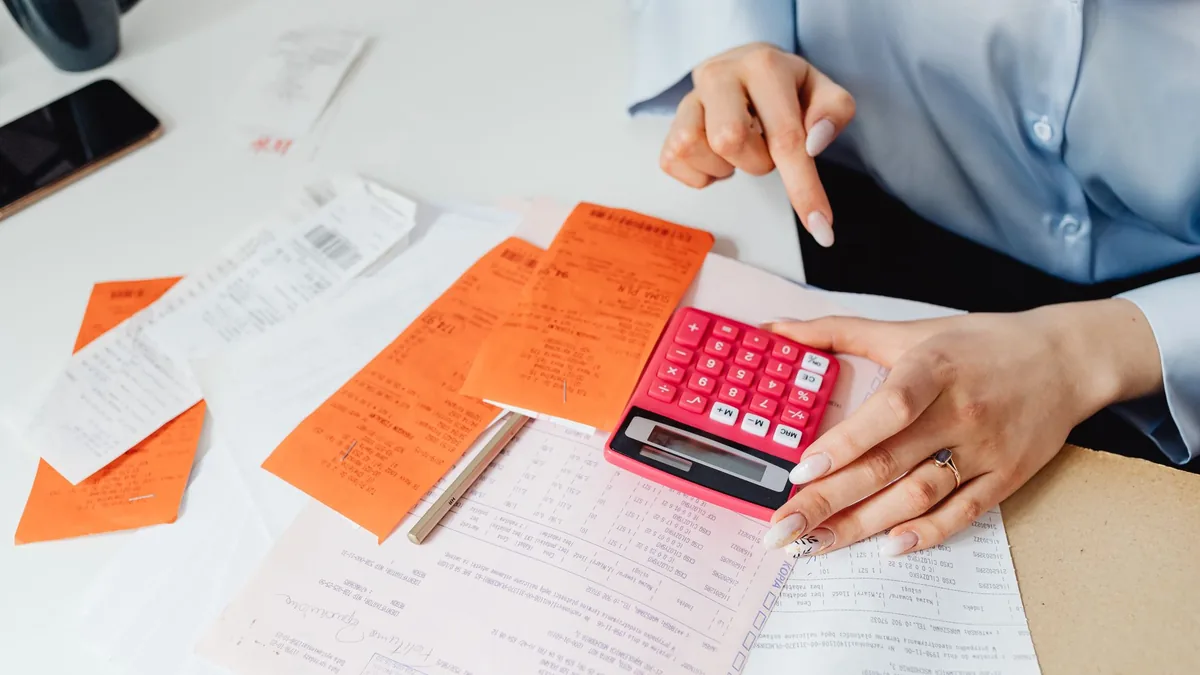 Pessoa analisando propostas com lupa e calculadora sobre documentos financeiros