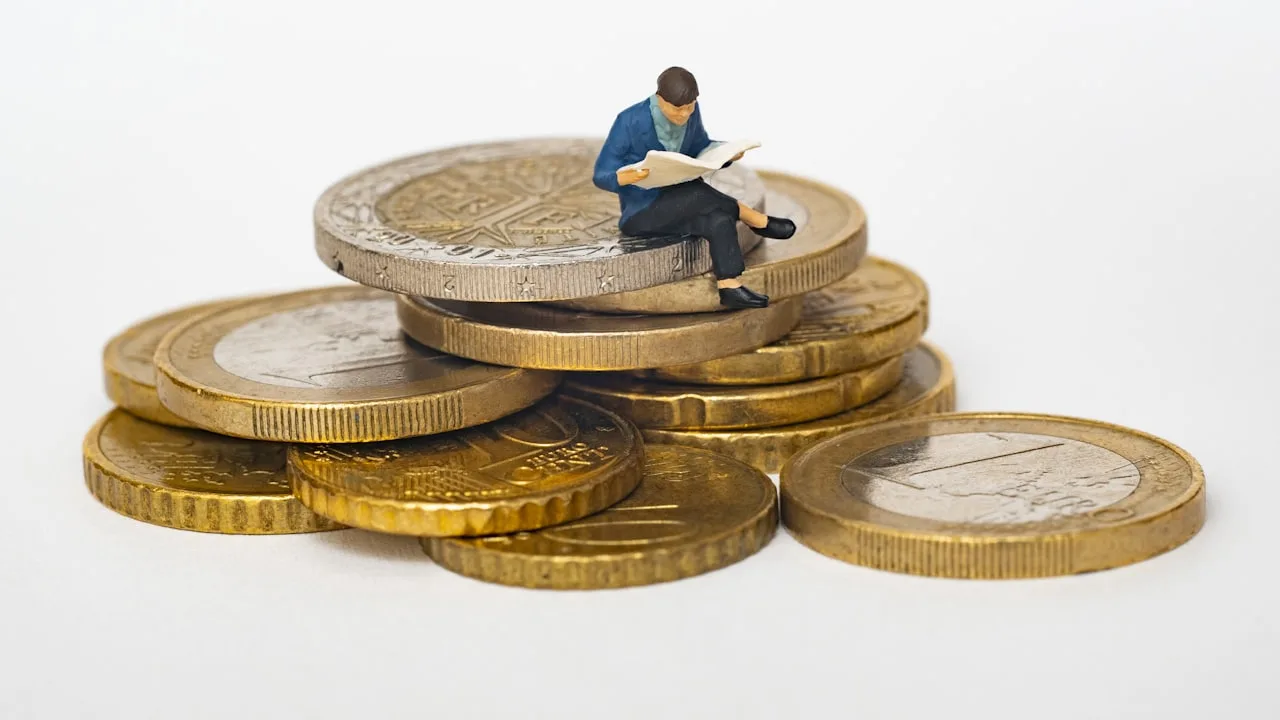 Mão depositando moeda em pote de poupança ao lado de calculadora