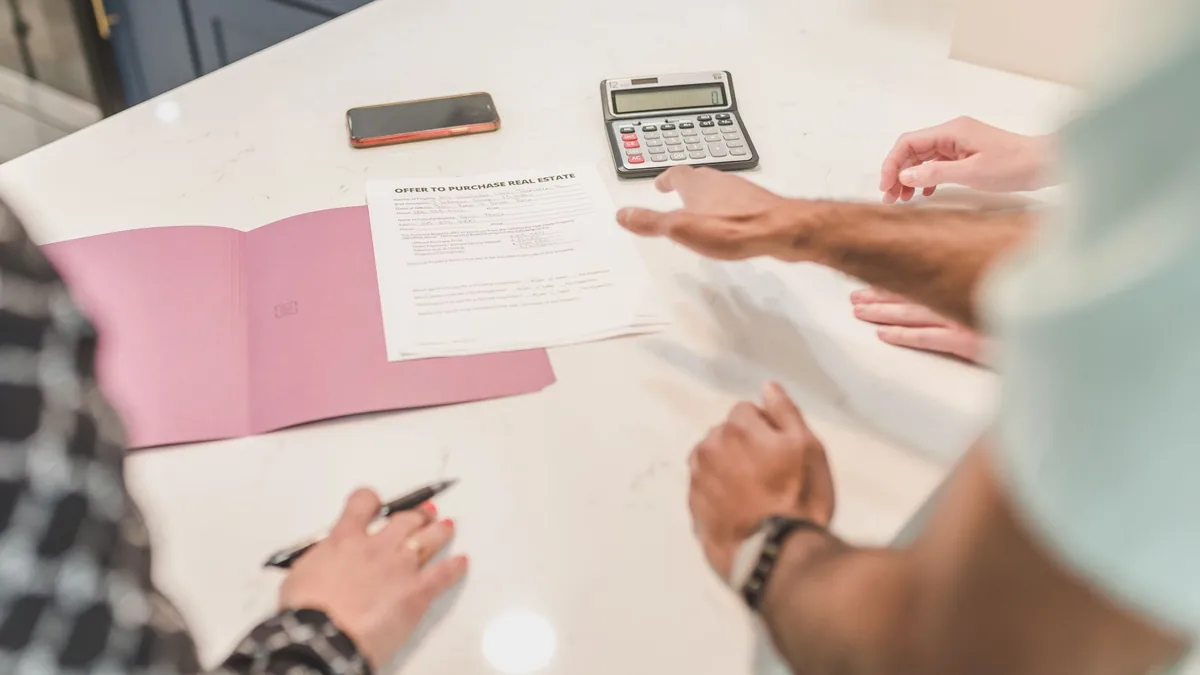 Mesa com calculadora, contrato de consórcio e anotações de comparação entre administradoras